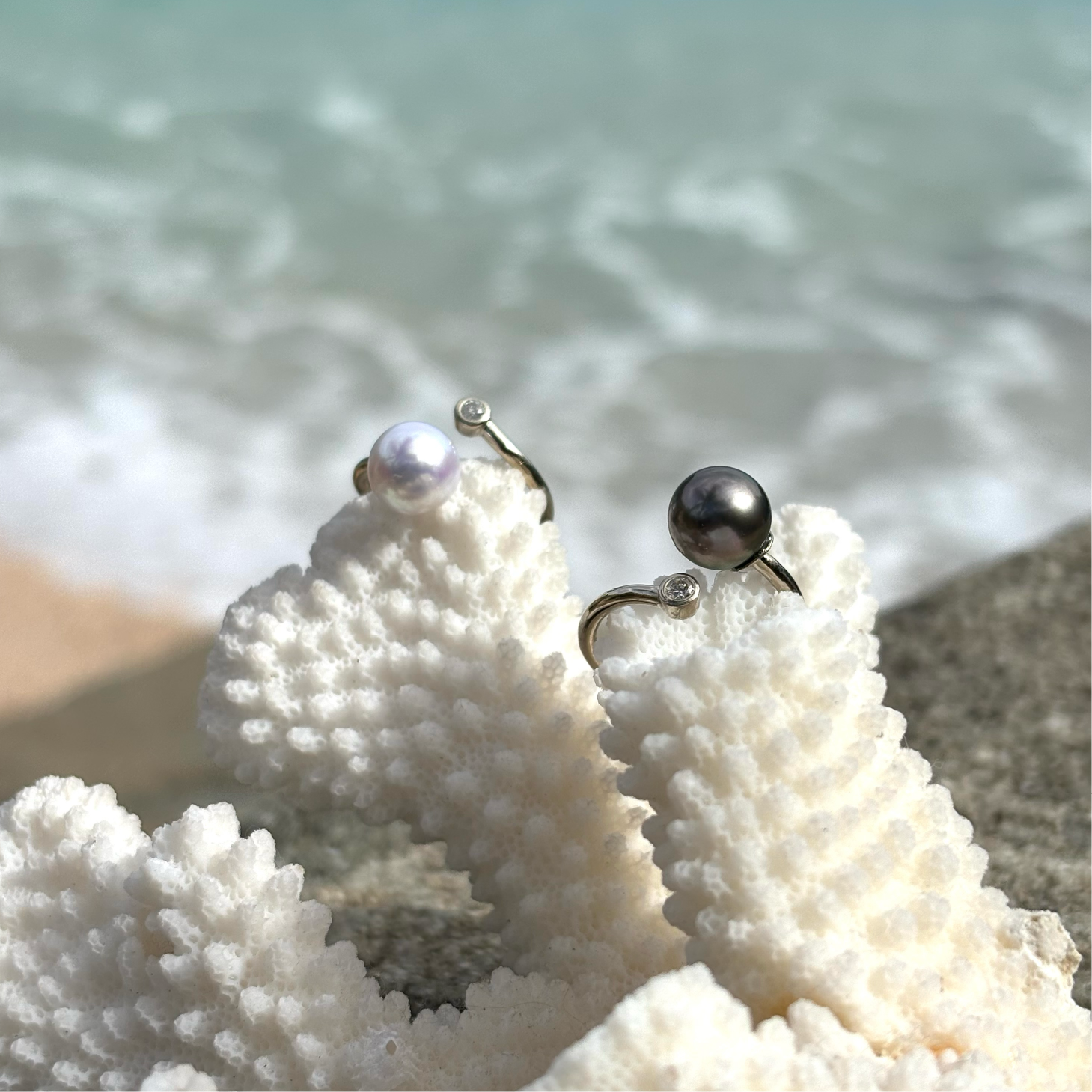 Adjustable white gold ring with a diamond and a Tahitian pearl displayed on coral by the sea
