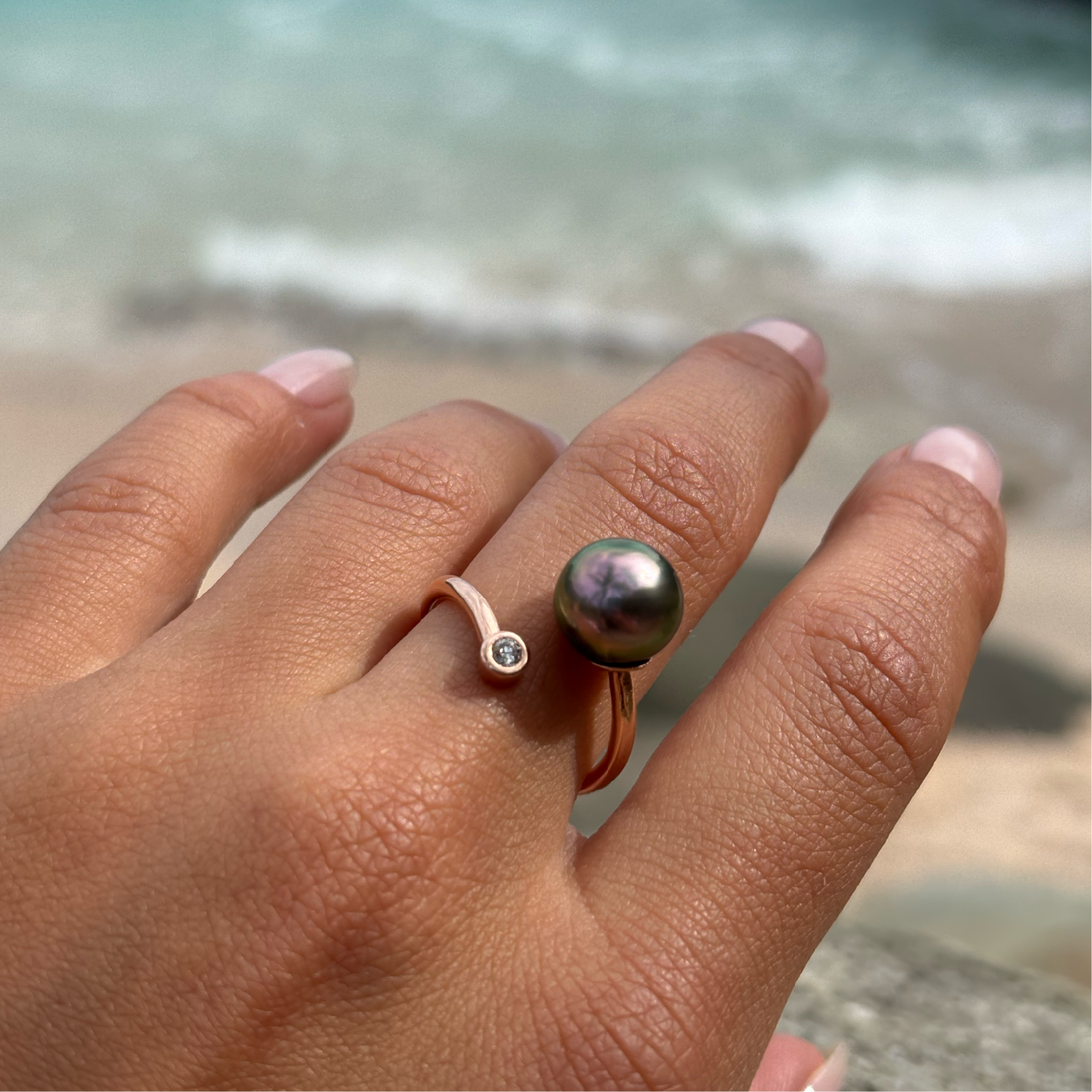 Adjustable rose gold ring with a diamond and a Tahitian pearl worn on the hand by the sea