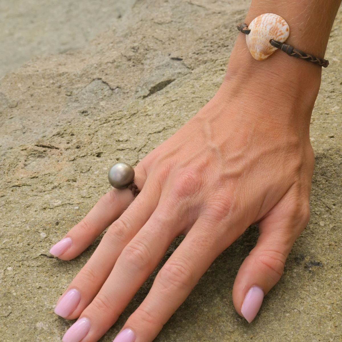 Bague en cuir tressé avec une perle de Tahiti de 15 mm portée à la main en gros plan