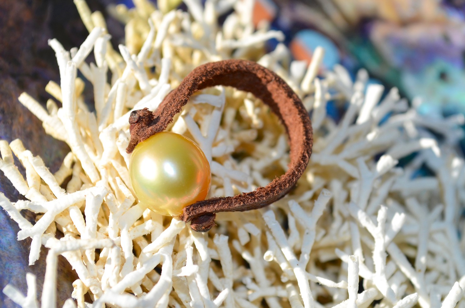 Leather ring with a 9 mm golden Australian South Sea pearl displayed on white coral