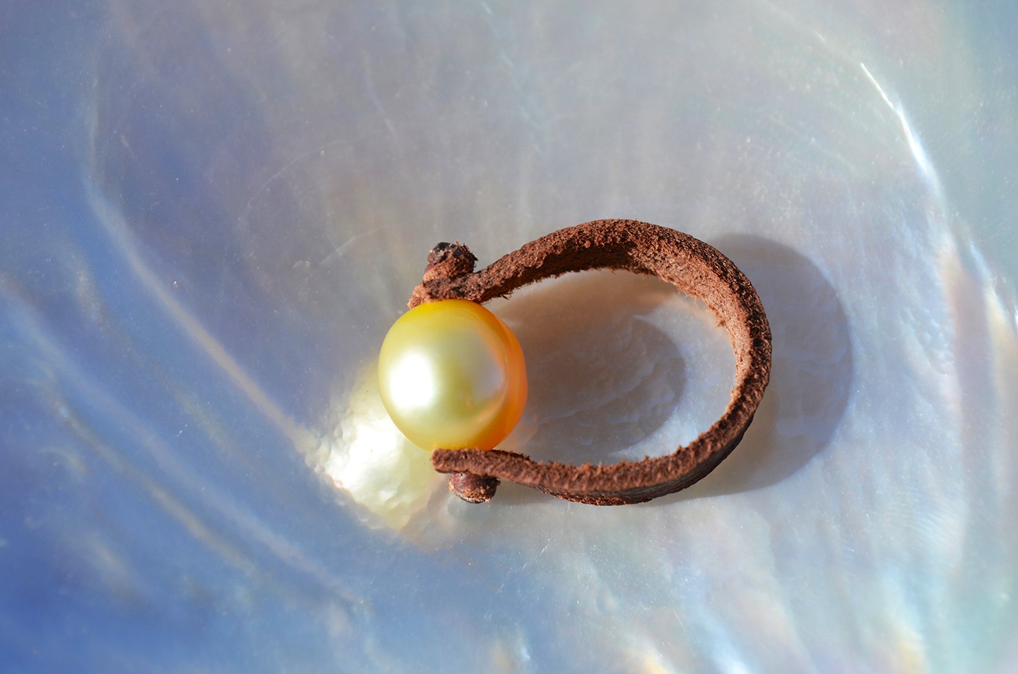 Leather ring with a 9 mm golden Australian South Sea pearl displayed on mother-of-pearl