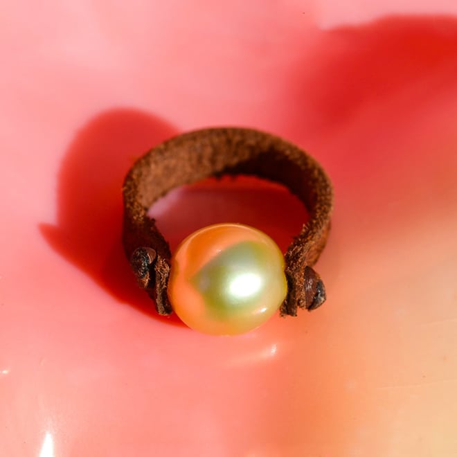 Brown leather ring with a 9 mm golden Australian South Sea cultured pearl shown against a pink background