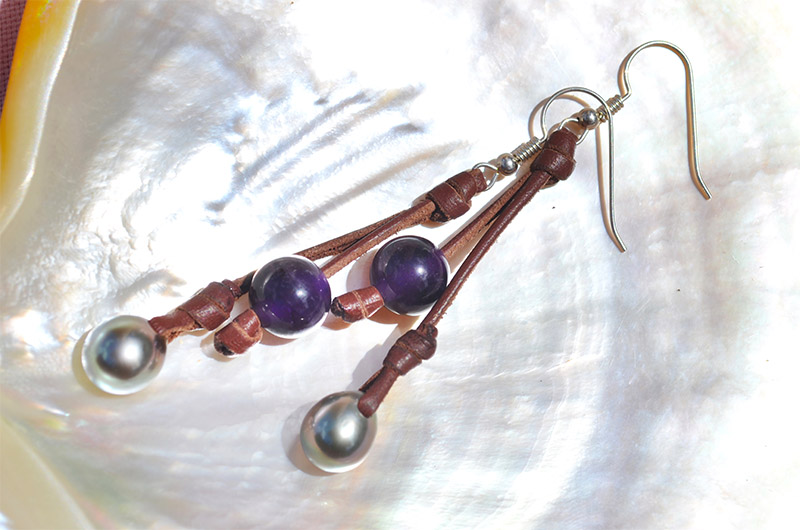 Leather earrings with amethysts and Tahitian pearls displayed on mother-of-pearl