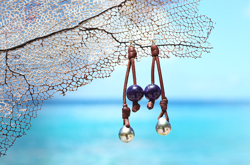 Leather earrings with amethysts and Tahitian pearls suspended from a sea fan by the sea