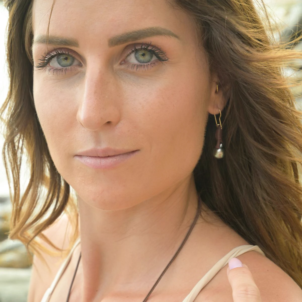 Close-up of leather earrings with drop-shaped Tahitian pearls being worn