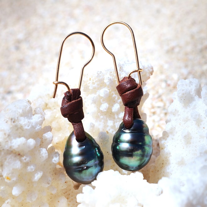 Brown leather drop earrings with two drop-shaped Tahitian pearls displayed on white coral
