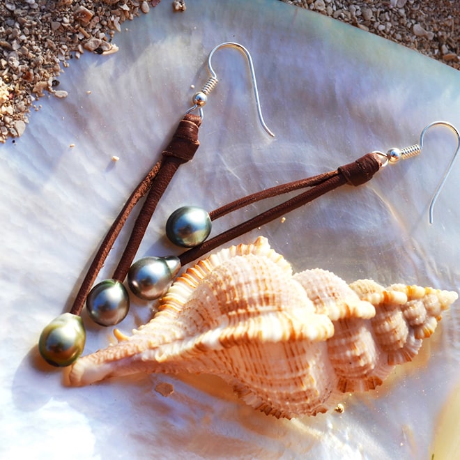 Brown leather drop earrings with four Tahitian pearls displayed on a seashell