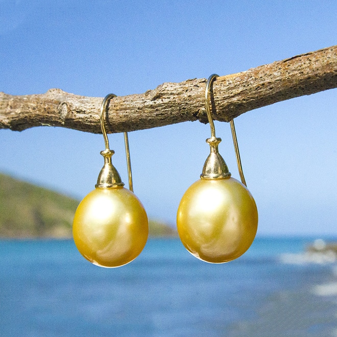 Boucles d’oreilles pendantes avec perles dorées d’Australie de 12 mm suspendues à du bois face à la mer