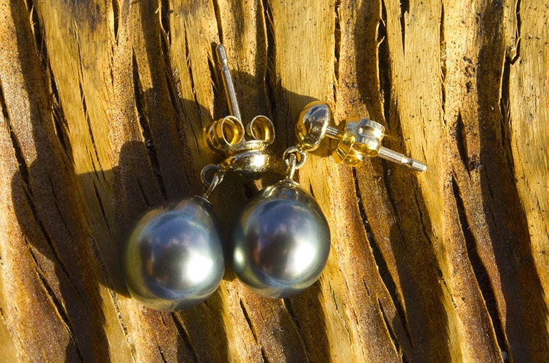 Earrings with 9.5 mm Tahitian pearls displayed on wood