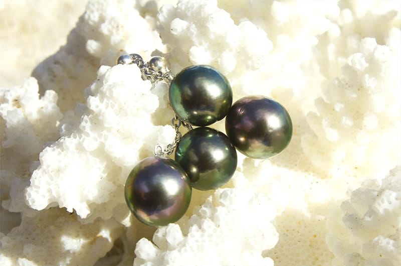 Sterling silver earrings with four Tahitian pearls displayed on white coral