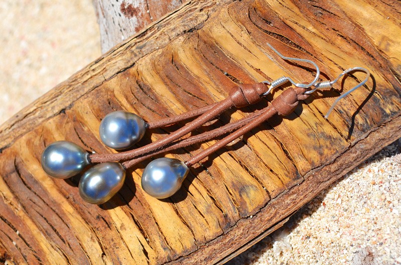 Leather earrings with four Tahitian pearls displayed on wood