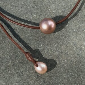 Ras du cou en cuir et grande perle rose de 14 mm, sur une pierre, détail.