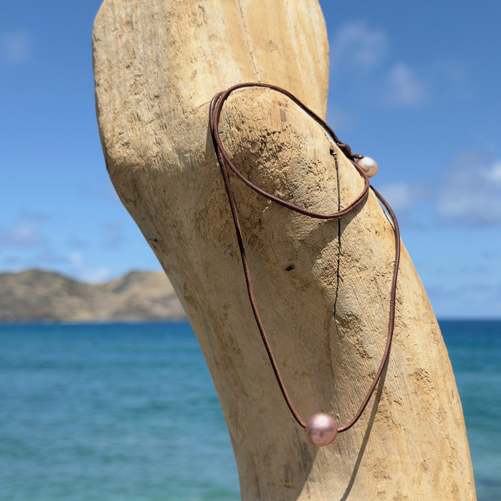 Ras du cou en cuir et grande perle rose de 14 mm, sur du bois.