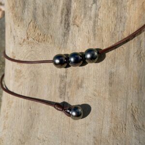 Ras du cou en cuir et trio de perles de Tahiti de 11,5 mm, sur du bois, détail.