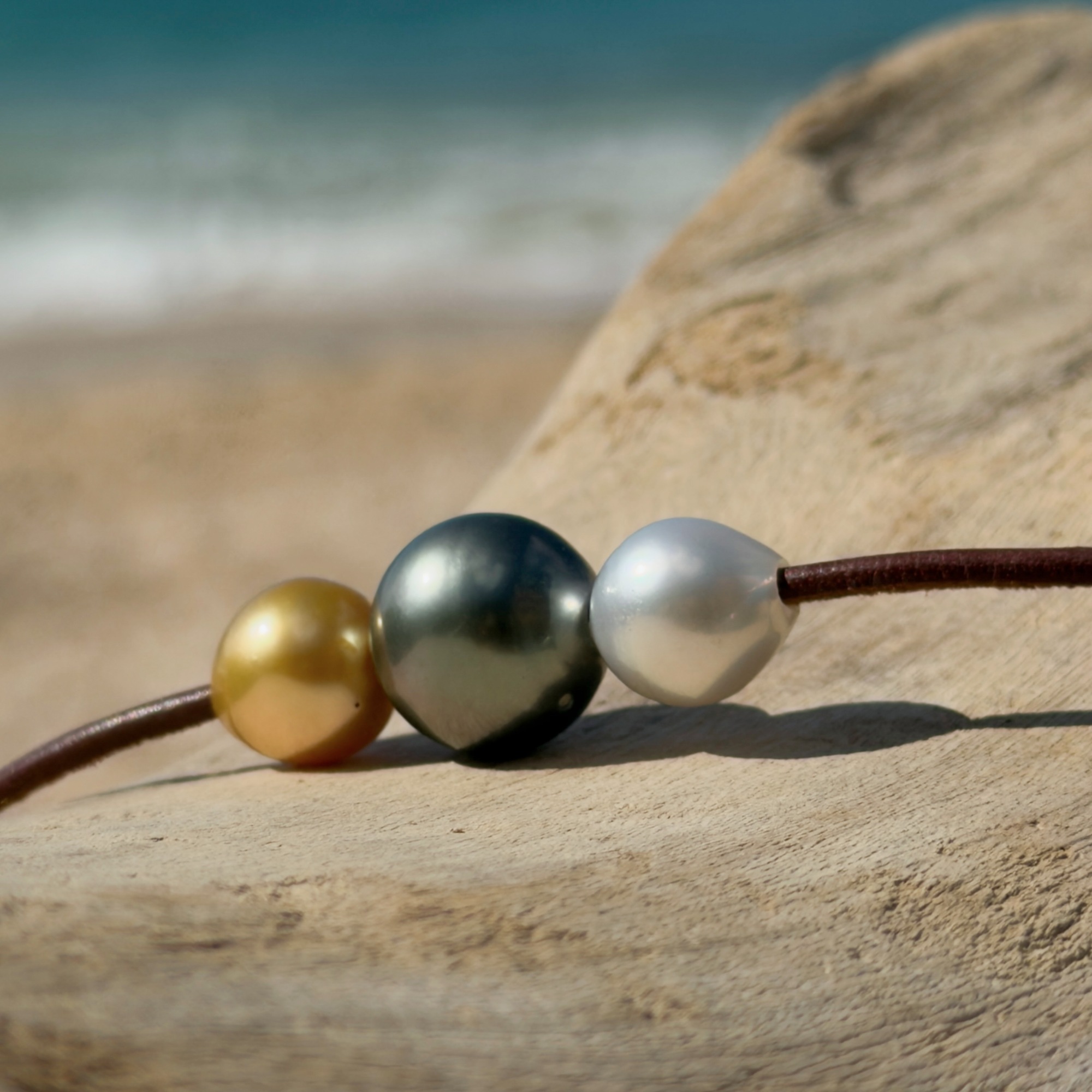 Ras du cou tricolore, perle de Tahiti et perles des mers du Sud, sur du bois, détail.