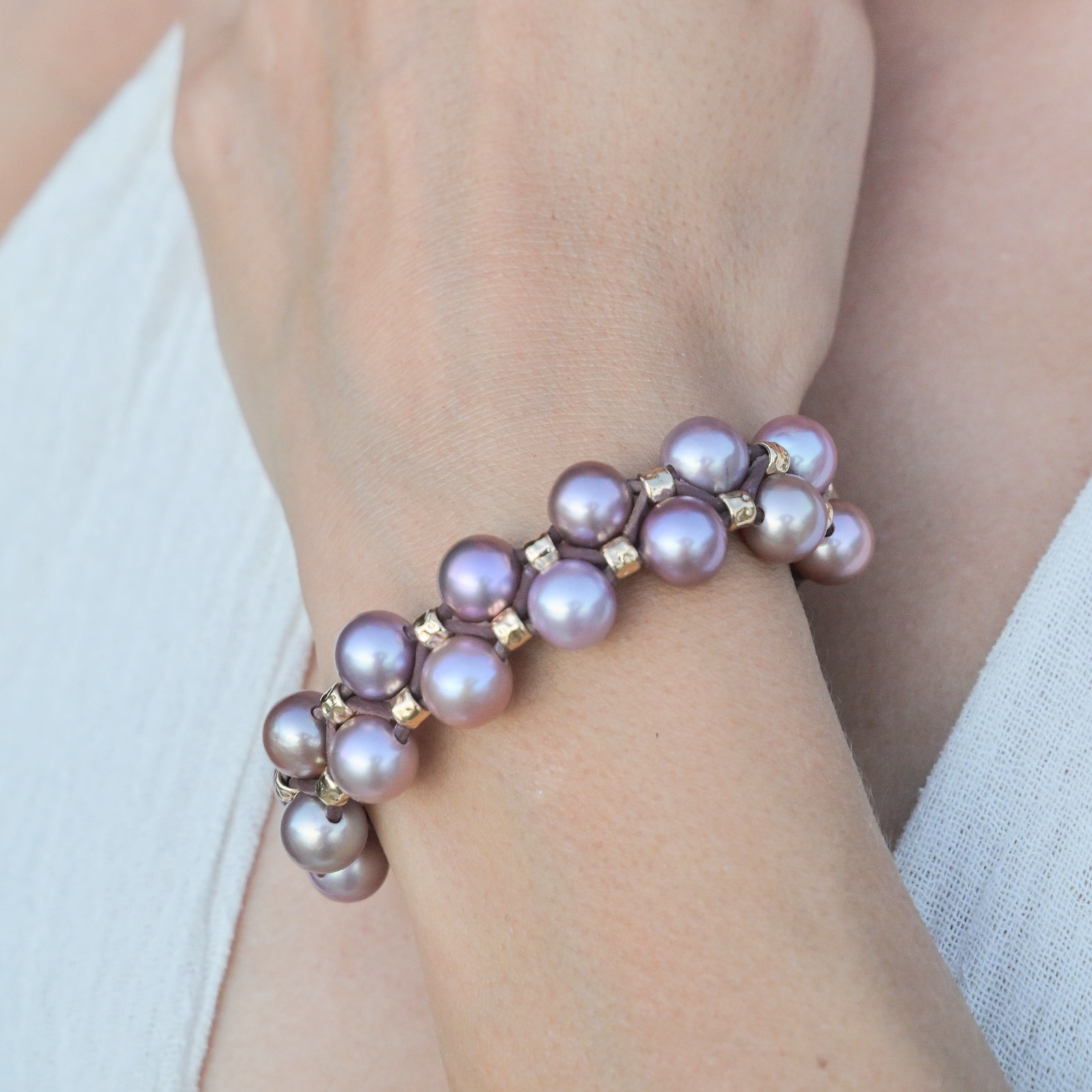 Double-row bracelet with pink pearls and hammered tubes, worn on the wrist.