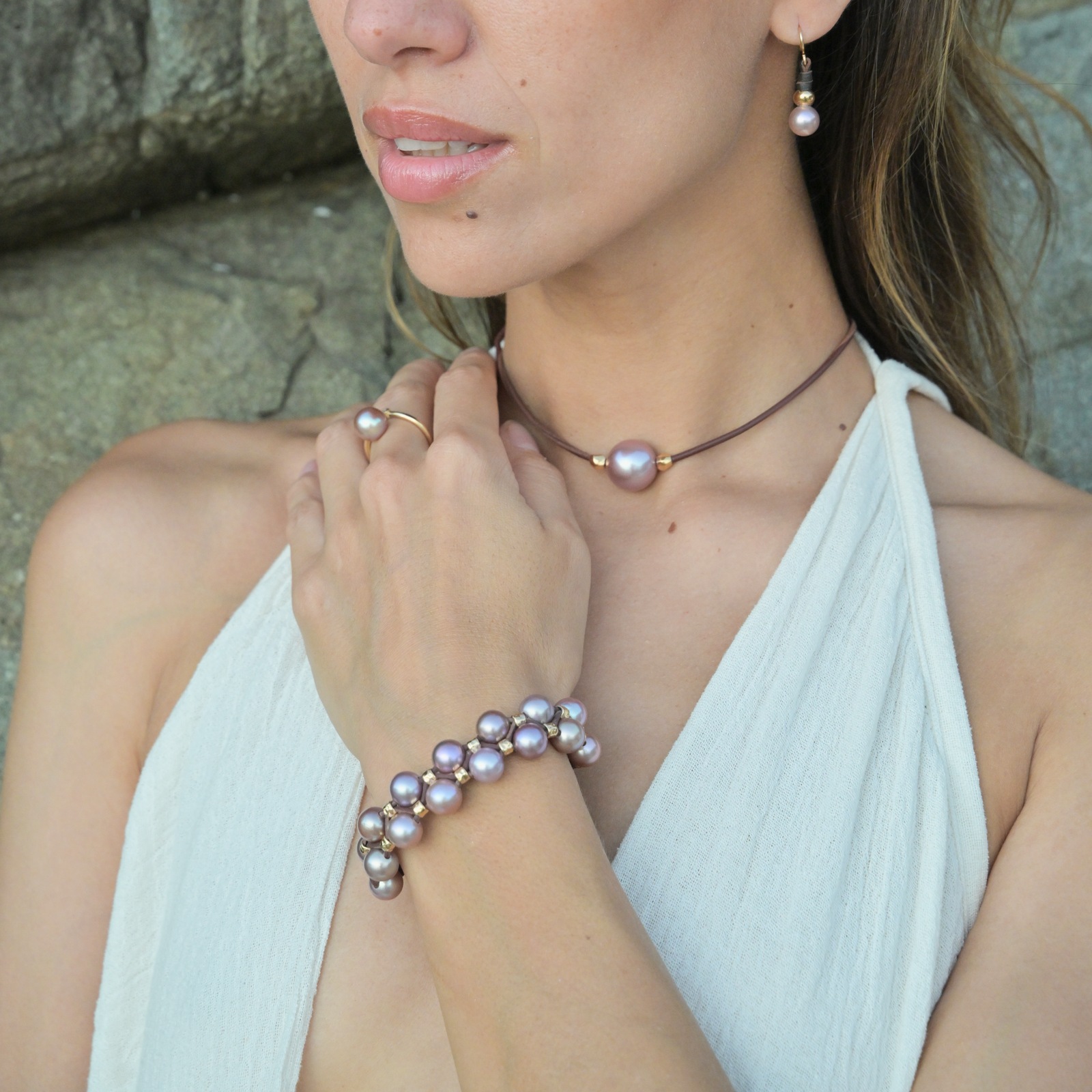 Double-row bracelet with pink pearls and hammered tubes, worn in context, square view around the bracelet.