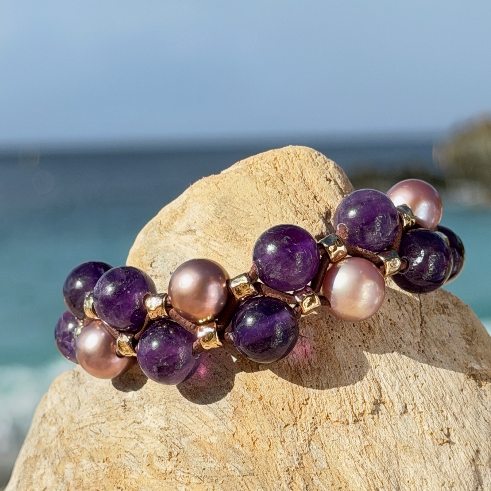 Bracelet double rang, perles roses et améthystes, sur du bois, détail.