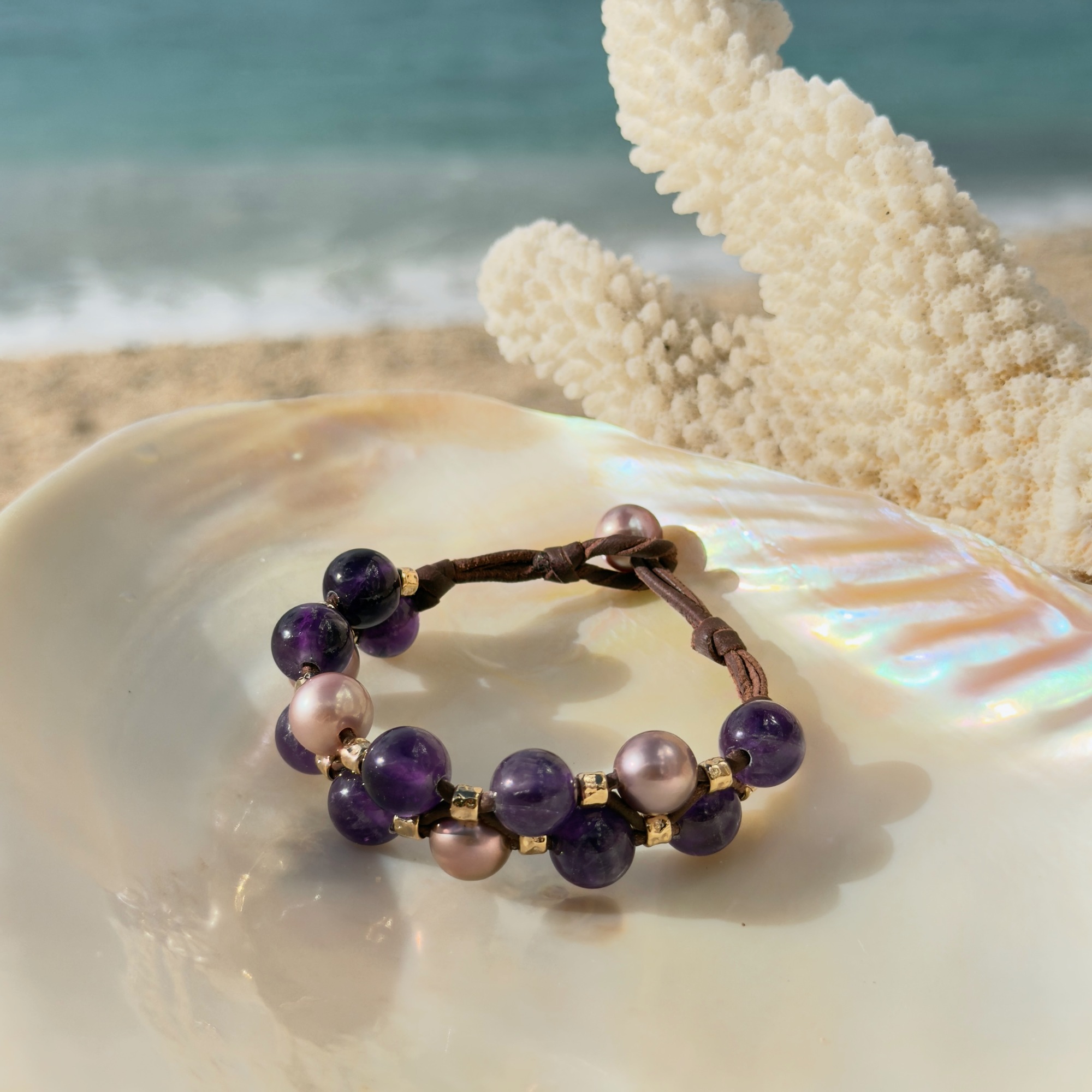 Bracelet double rang, perles roses et améthystes, sur un coquillage.