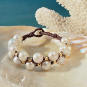 Bracelet double rang, perles blanches et tubes martelés, sur un coquillage.