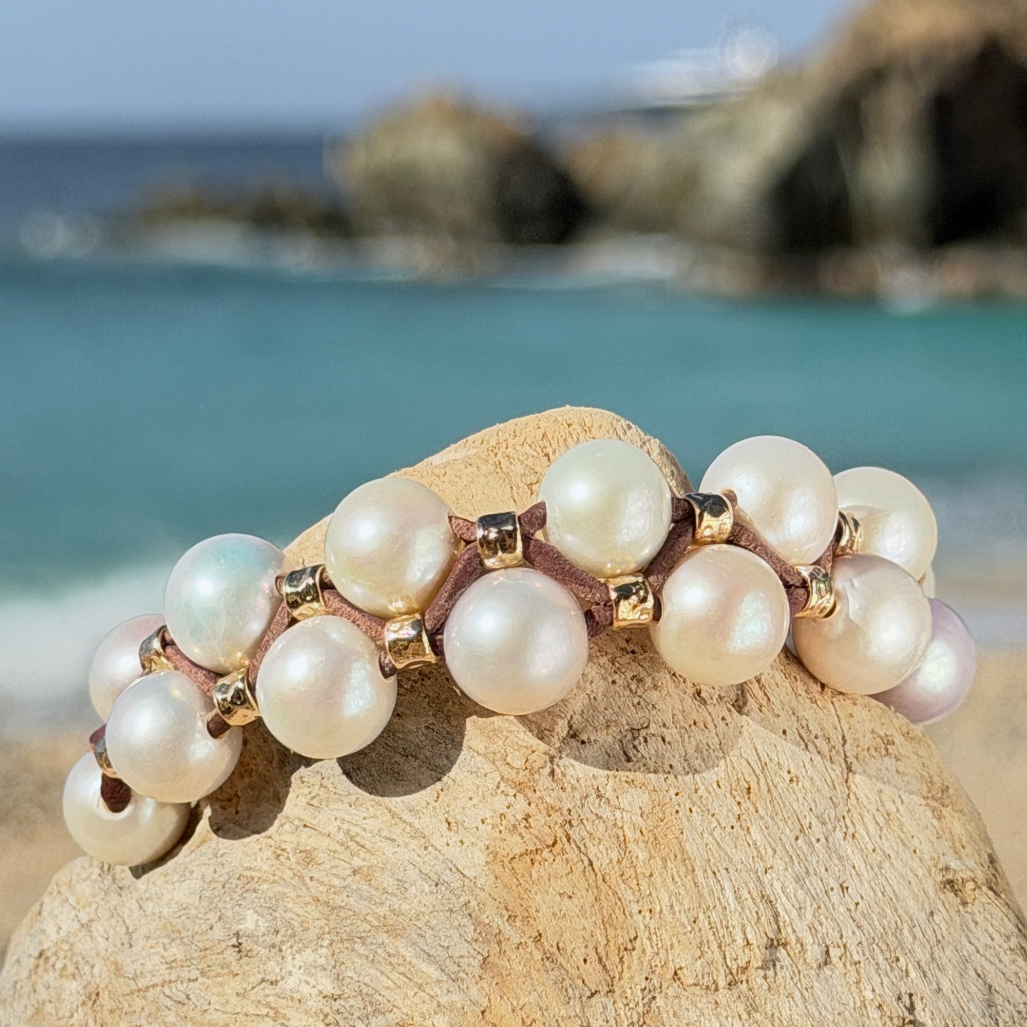 Double-row bracelet with white pearls and hammered tubes, on wood.