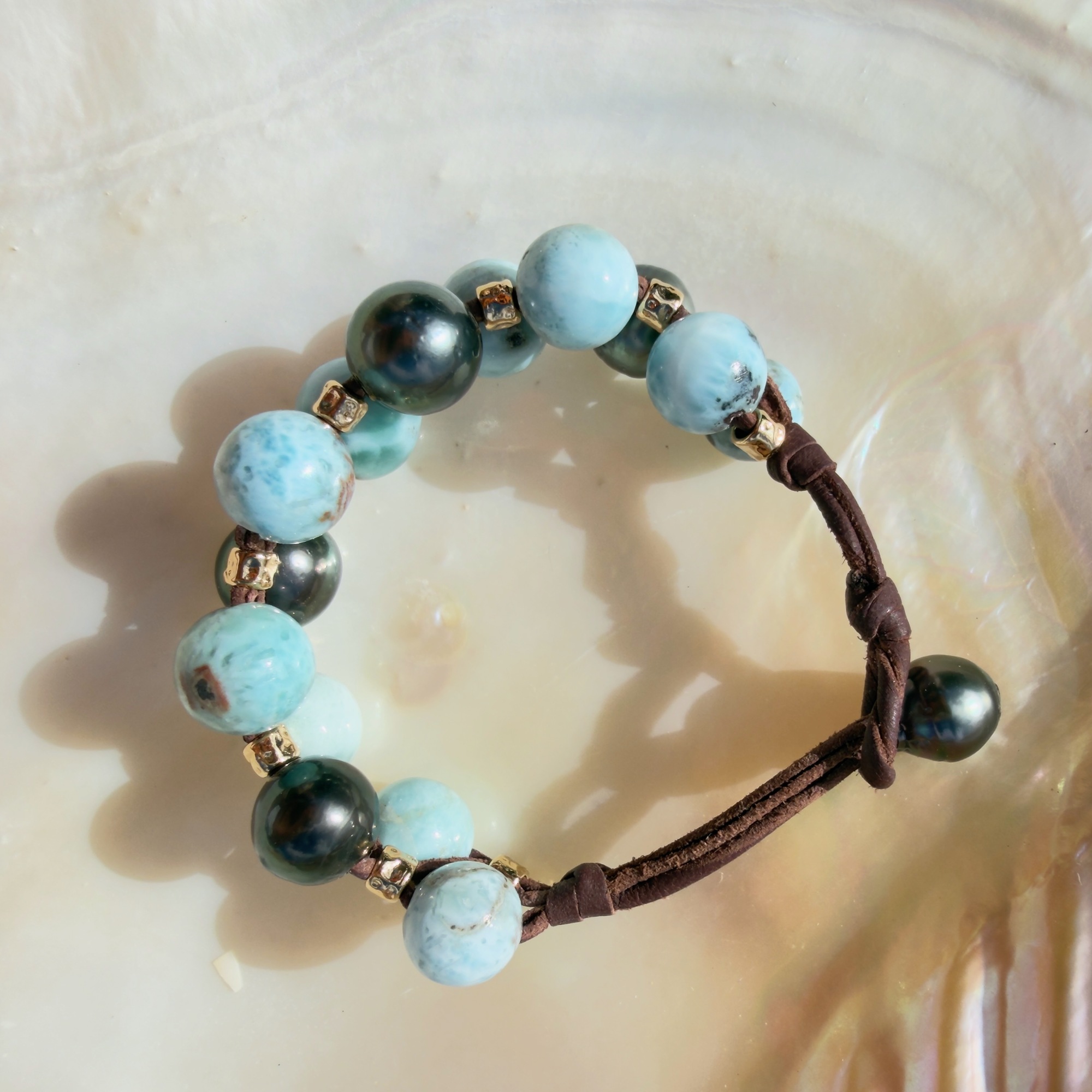 Bracelet double rang, Larimar et perles de Tahiti, sur un coquillage, vue de dessus.