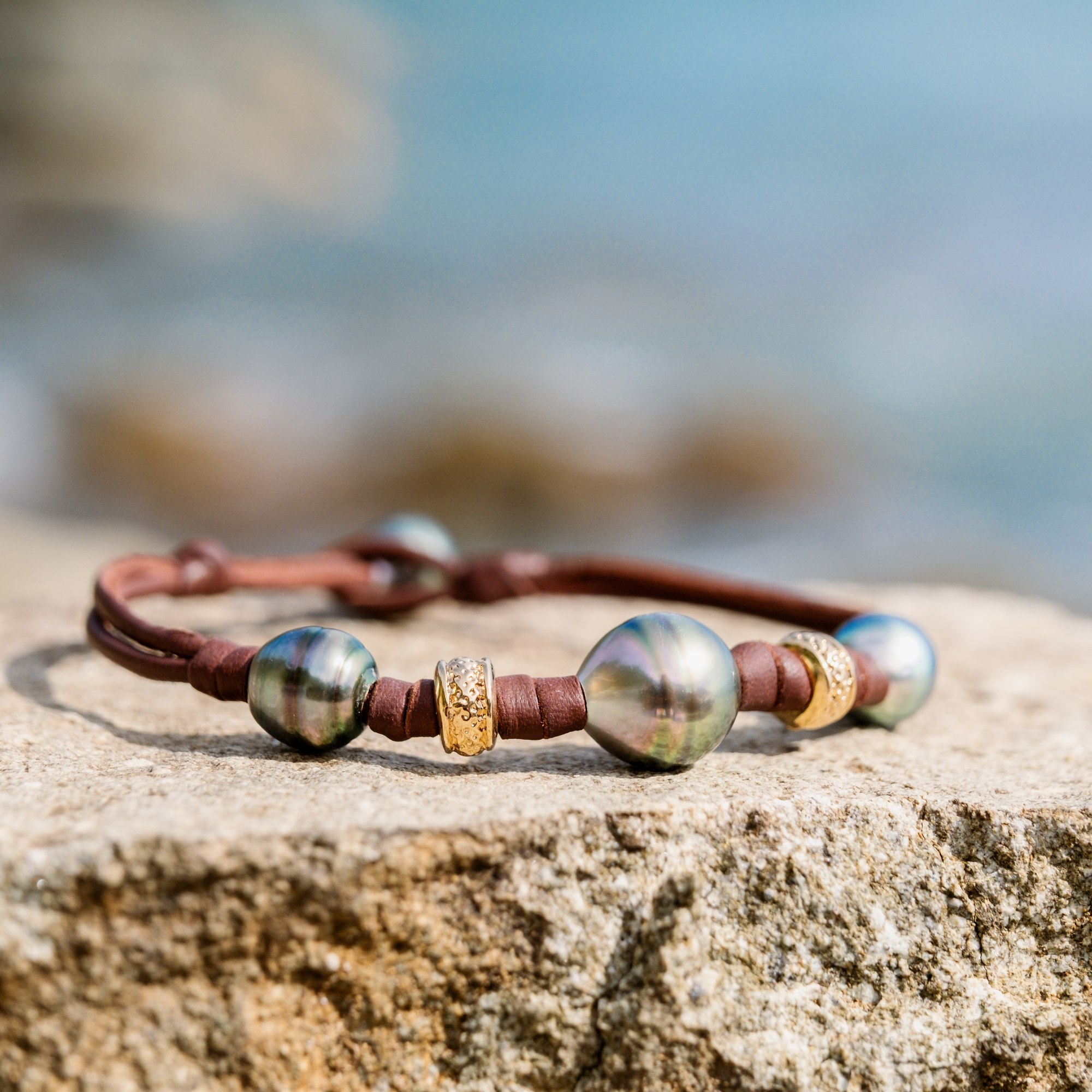 Bracelet en cuir, trois perles baroques de Tahiti et rondelles dorées, sur une pierre, détail.