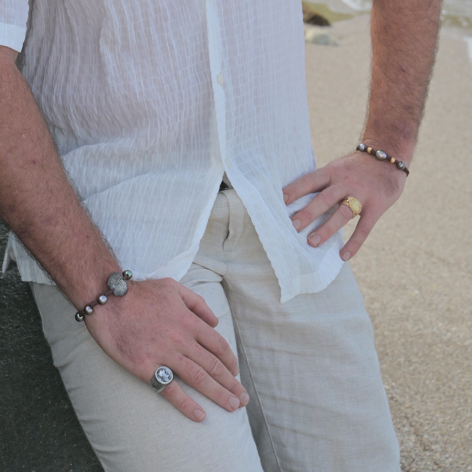 Bracelet en cuir, trois perles baroques de Tahiti et rondelles dorées, vue portée rapprochée montrant les deux mains entières.