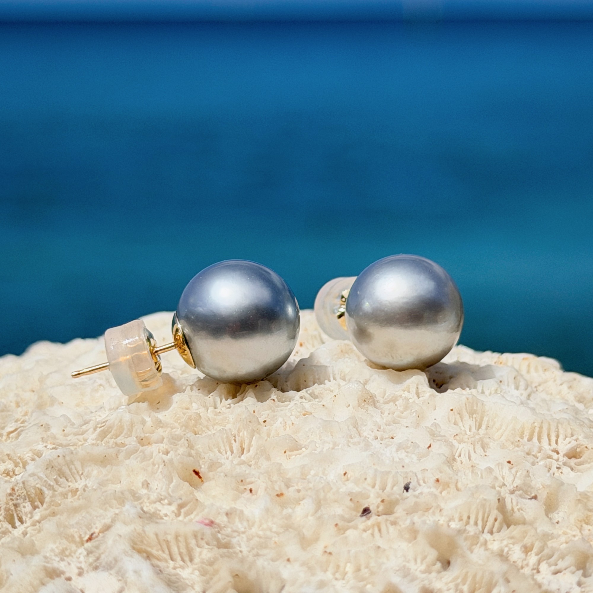 Clous en or et perles de Tahiti, sur un support de corail.