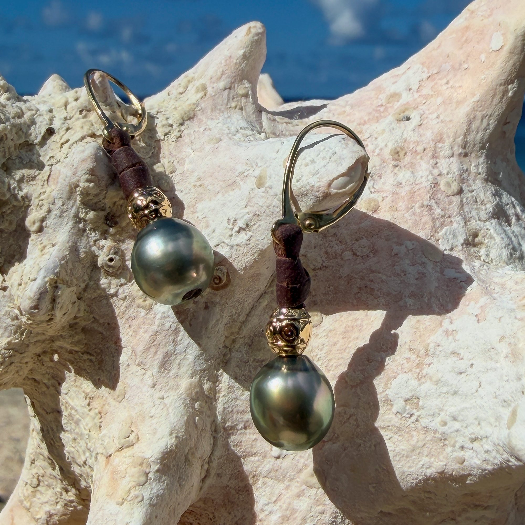 Boucles en cuir, perles de Tahiti et éléments ciselés, sur un coquillage.