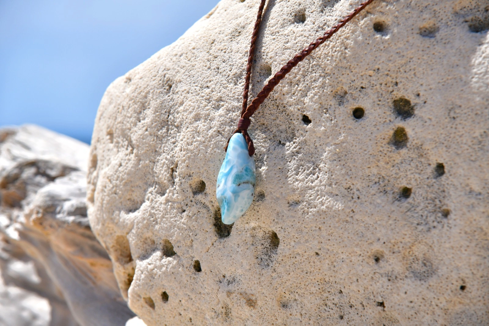 Close-up of the Larimar pendant and braided leather on a rock
