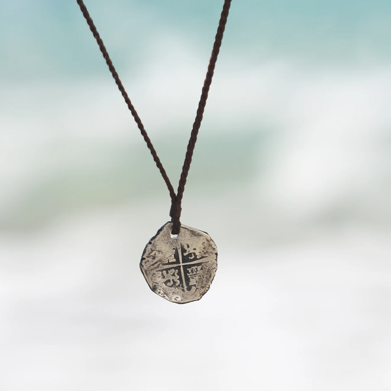 Braided kangaroo leather necklace with an antique silver eight reales coin mounted as a pendant