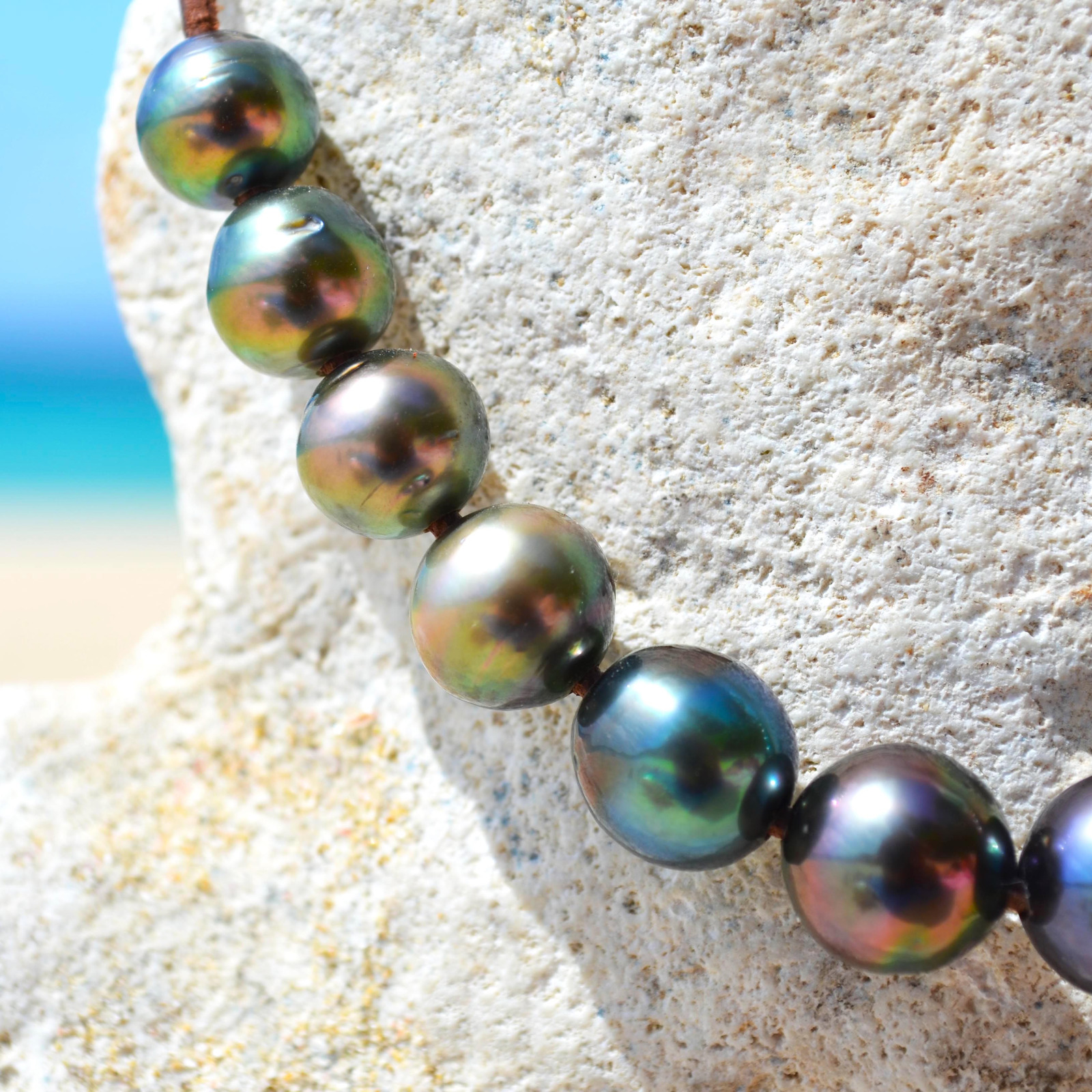 Close-up of the multicolored Tahitian cultured pearls on the choker displayed on a rock by the sea
