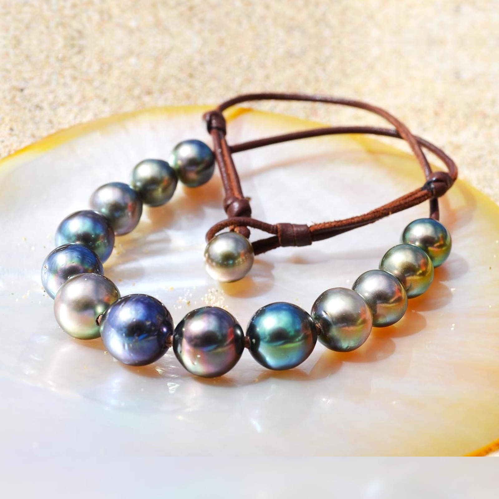 Brown leather choker with 14 multicolored Tahitian cultured pearls displayed on mother-of-pearl