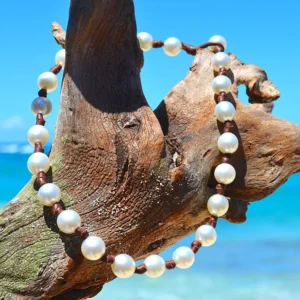 Collier ras du cou en cuir avec 23 perles de culture blanches des mers du Sud présenté sur du bois flotté à la plage
