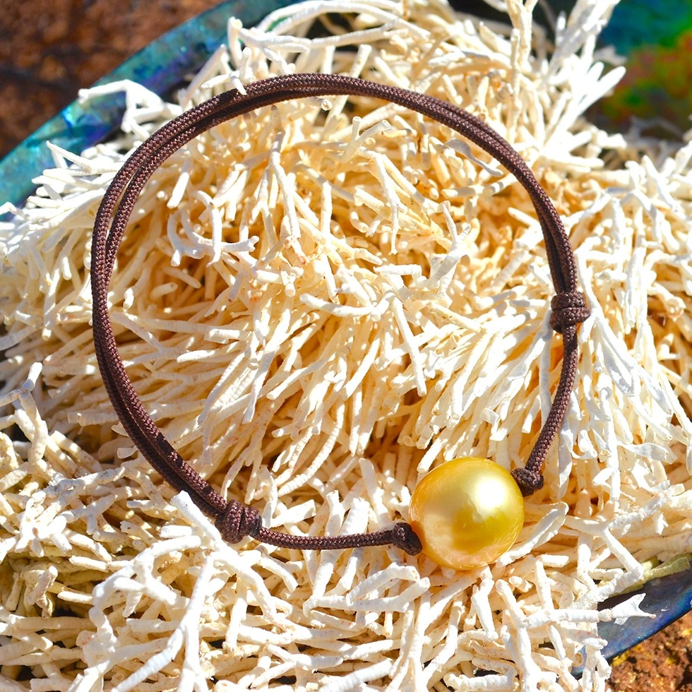 Bracelet ajustable avec une perle dorée d’Australie de 11,5 mm présenté sur un coquillage
