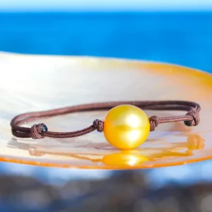 Bracelet ajustable avec une perle dorée d’Australie de 11,5 mm présenté sur une nacre face à la mer