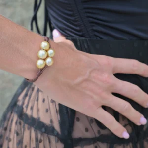 Leather bracelet with five golden Australian pearls worn on the wrist in close-up