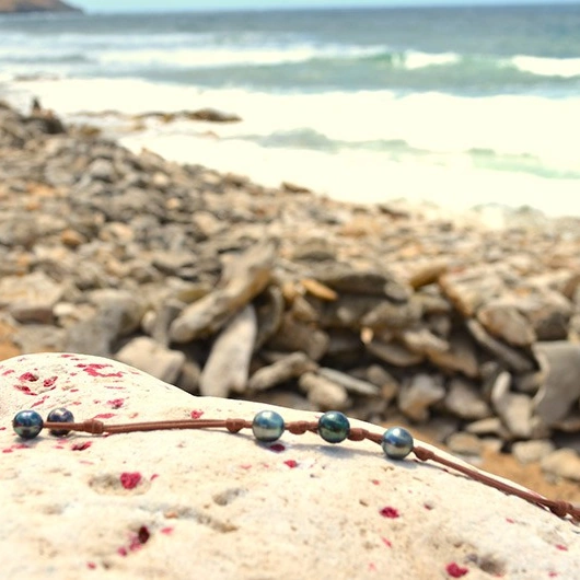 Bracelet en cuir marron déployé avec trois perles de Tahiti et deux perles de fermeture au bord de mer
