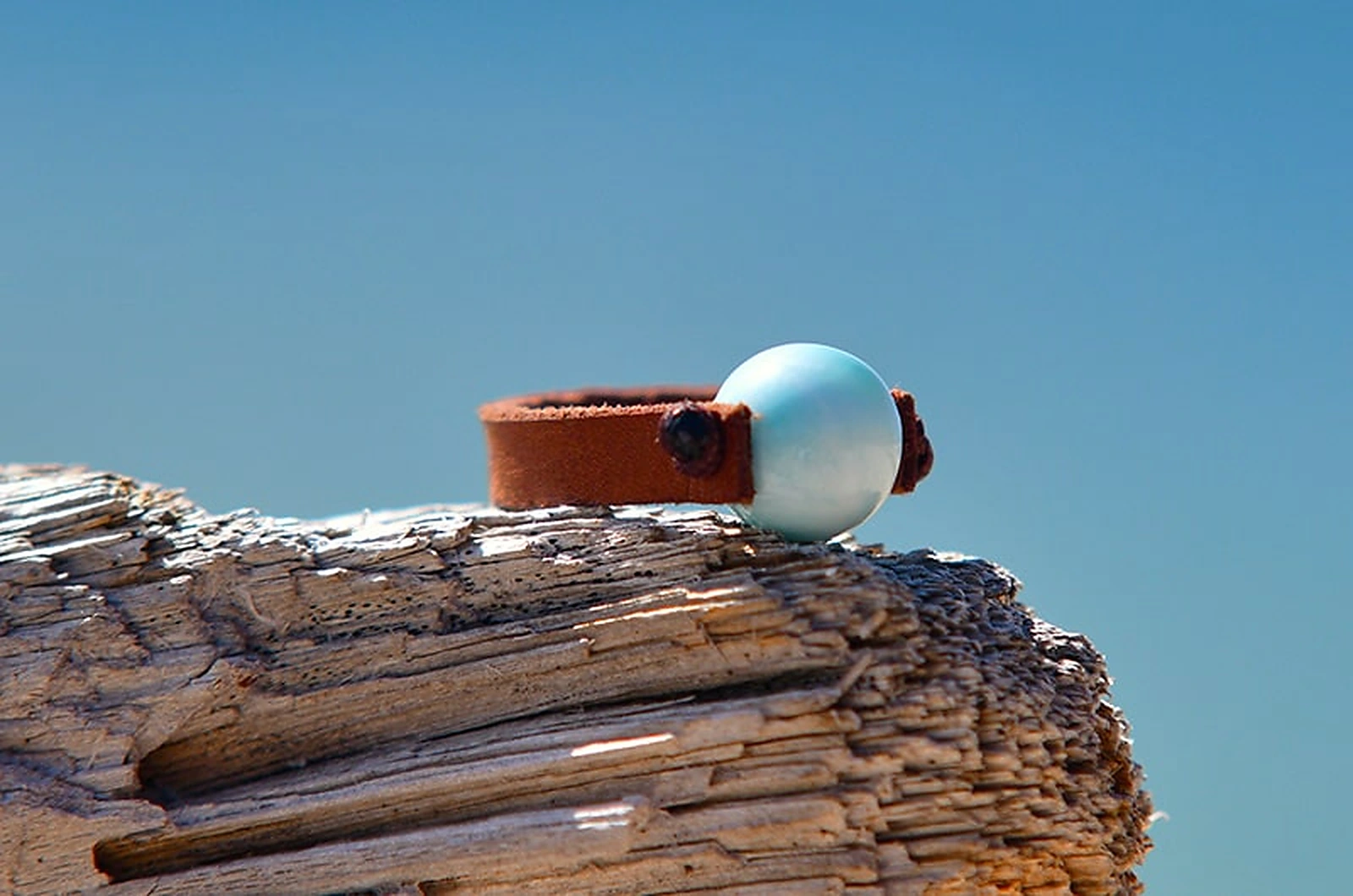 Brown leather ring with a round 10 mm Larimar displayed on a rock