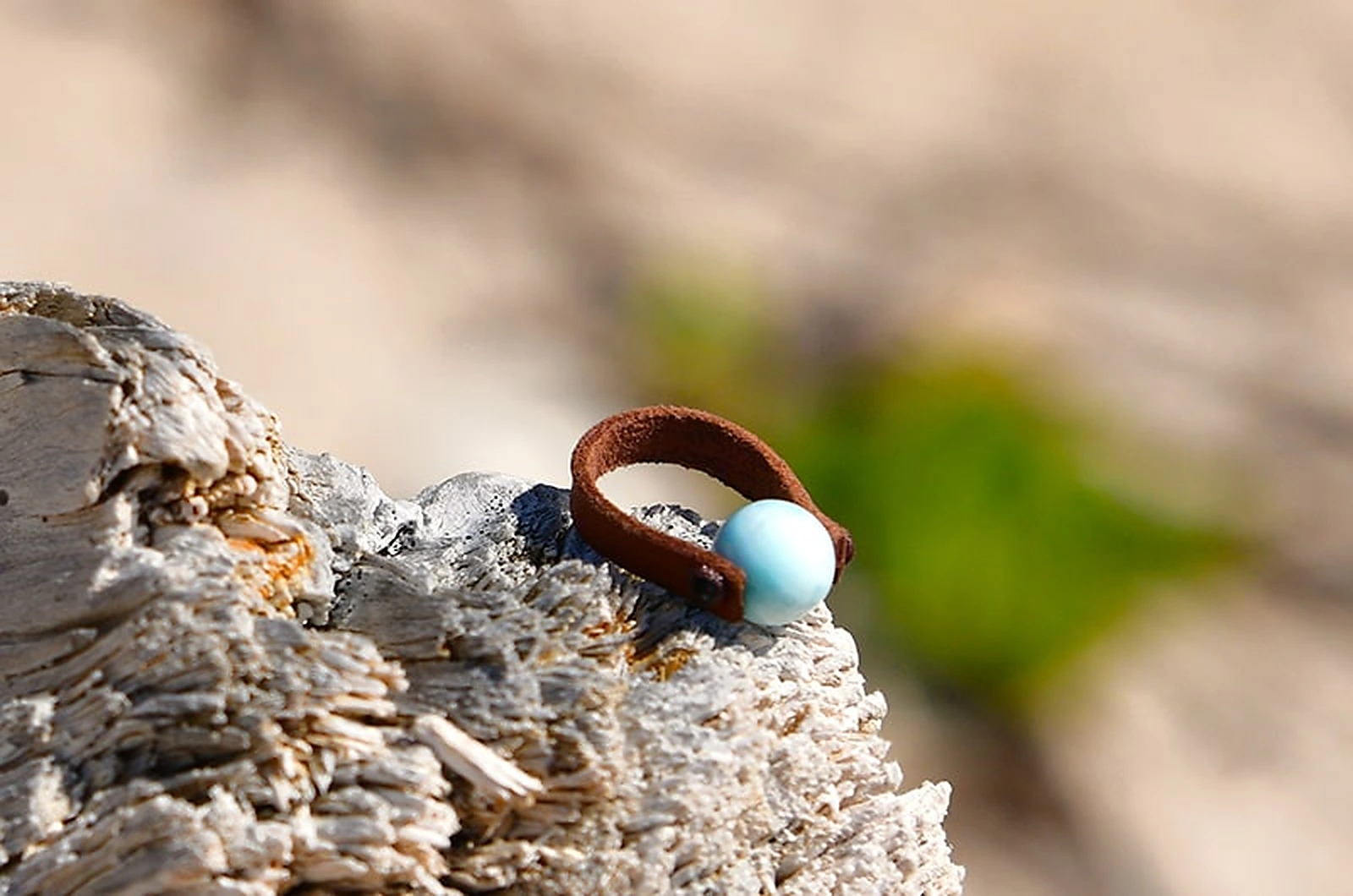 Front view of the brown leather ring with a round 10 mm Larimar displayed on driftwood