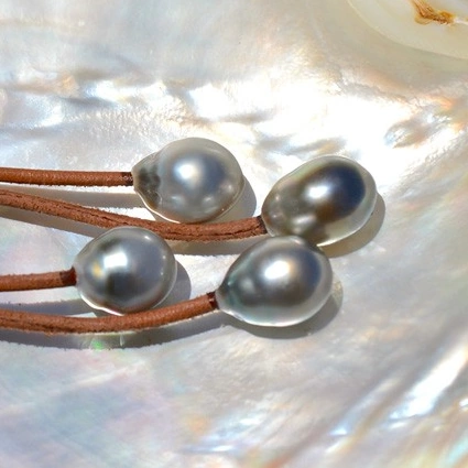 Brown leather drop earrings with four Tahitian pearls displayed on mother-of-pearl
