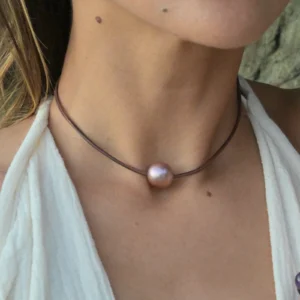 Leather choker with a large 14 mm pink pearl, worn around the neck.
