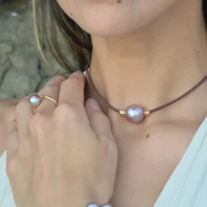 Ras du cou en cuir, perle rose et billes en plaqué or, au cou.