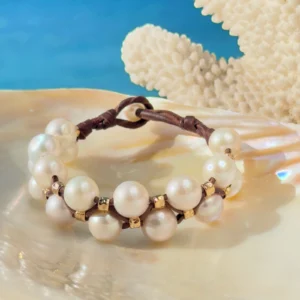 Bracelet double rang, perles blanches et tubes martelés, sur un coquillage.
