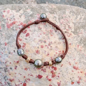 Bracelet en cuir, trois perles baroques de Tahiti et rondelles dorées, sur une pierre, vue de dessus.