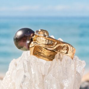 Bague Baroque en or et perle de Tahiti, sur un support cristallin, vue de côté.