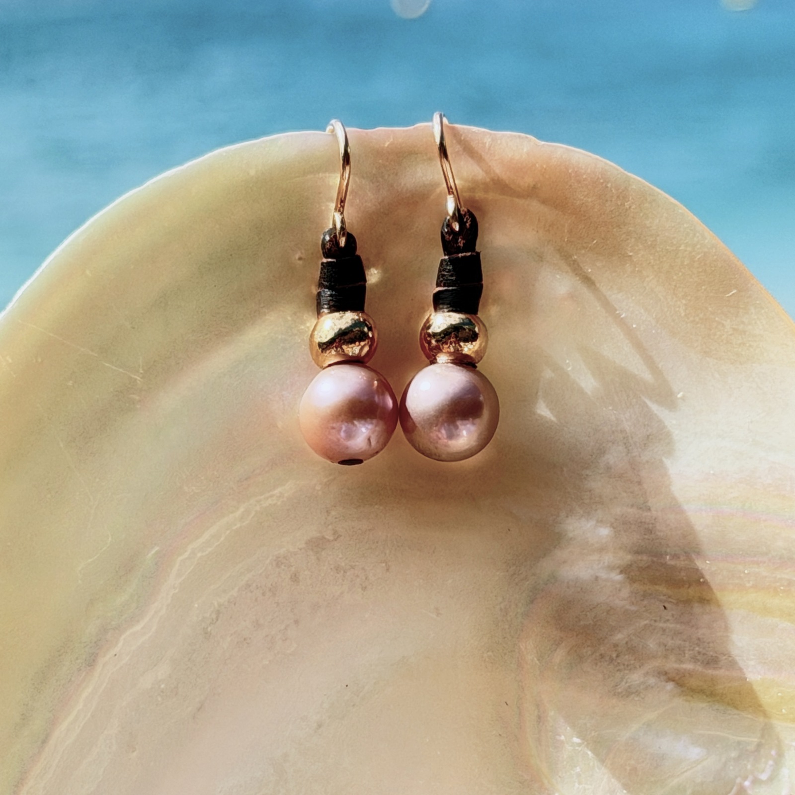 Boucles en cuir, perles roses et crochets en or 18 carats, sur un coquillage.
