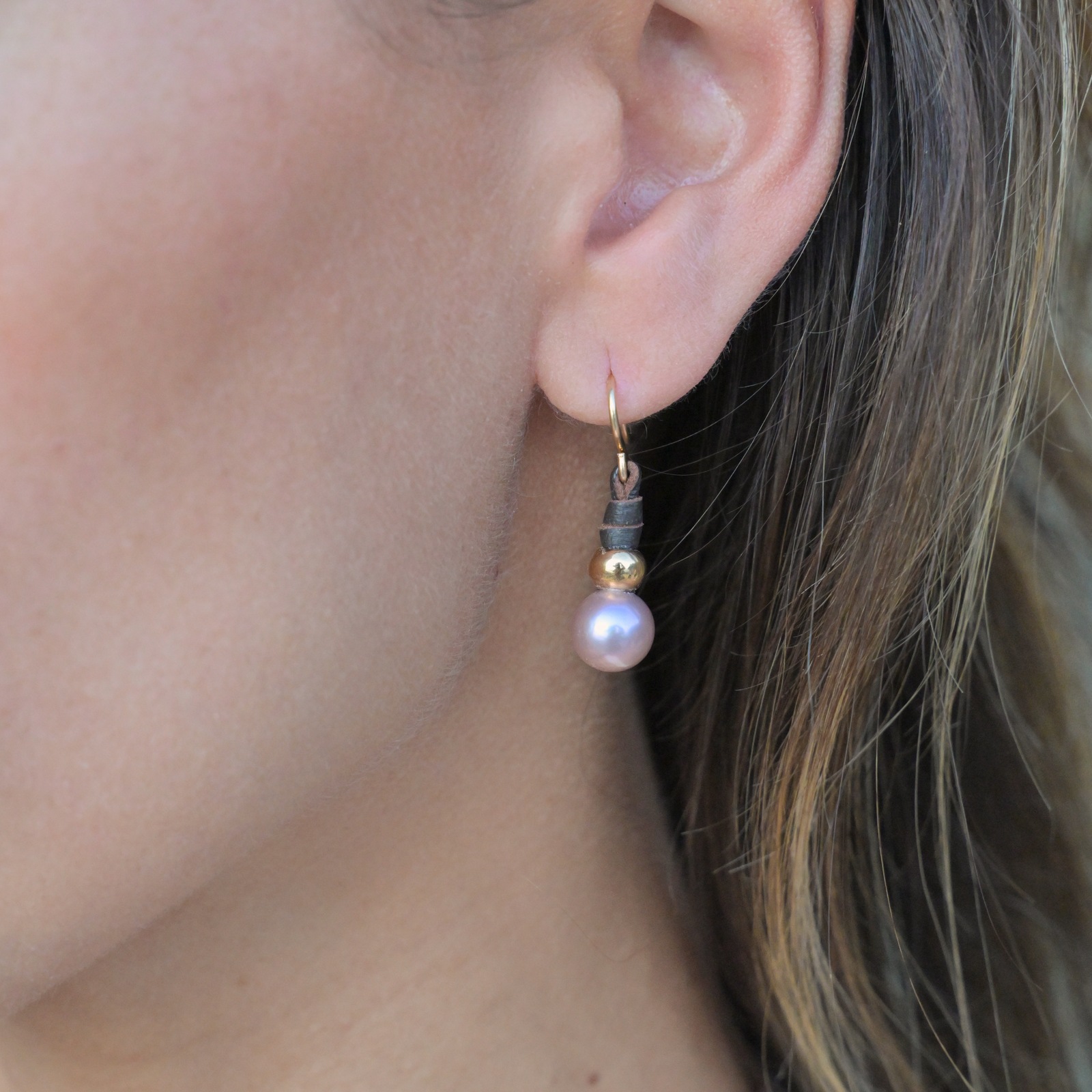 Boucles en cuir, perles roses et crochets en or 18 carats, à l’oreille.