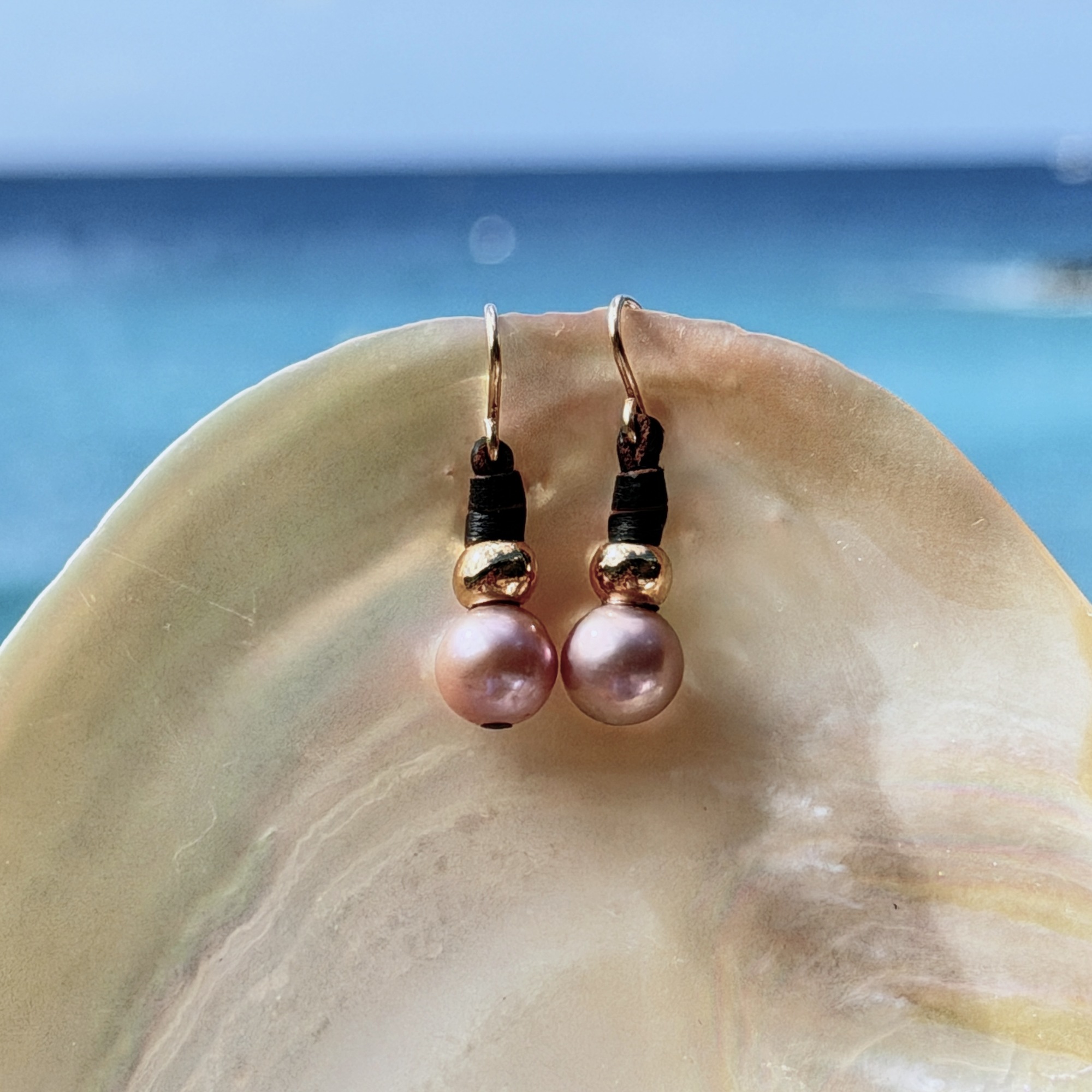 Boucles en cuir, perles roses et crochets en or 18 carats, sur un coquillage.